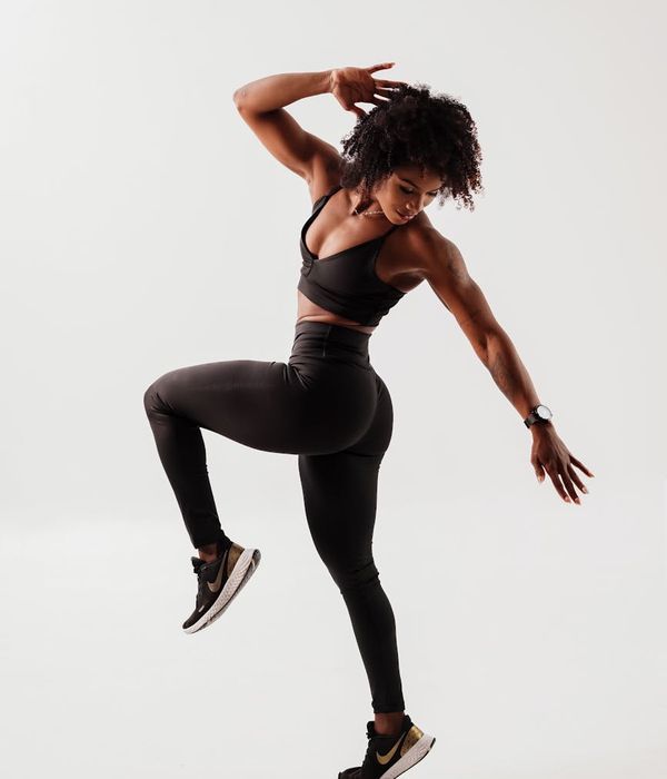 Woman in a dynamic yet graceful cardio movement pose indoors.